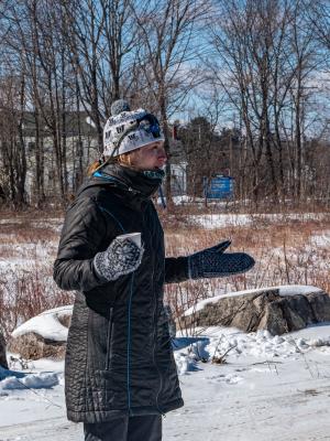 Leah Hart, in a winter hat and coat, speaks to attendees outdoors at Champlin Forest.