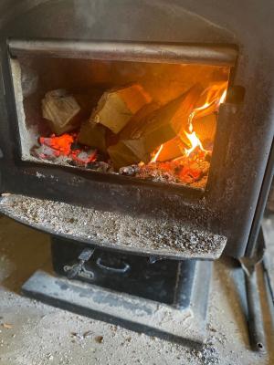 Woodstove open door reveals coals under dry logs