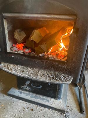 Woodstove open door reveals coals under dry logs