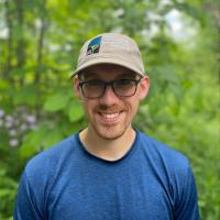 Nate poses outside with a Forest Society hat on his head.