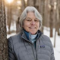 Susan Arnold poses outside in winter next to a tree.