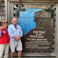 Jane in red and Dave in blue stand with historical sign for Old Man Mountains