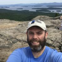 Derek Colquhoun poses on the summit of Mount Major with the lake behind him.