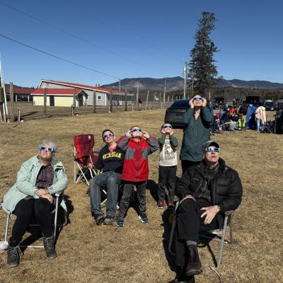 A family looks up at the sun with eclipse glasses on.