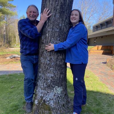 Two people stand on either side of a tree
