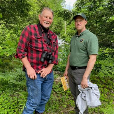 Dave Anderson and John Magee pose in front of the river with the book.