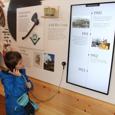 A child listens to audio from an exhibit in the Carriage Barn.