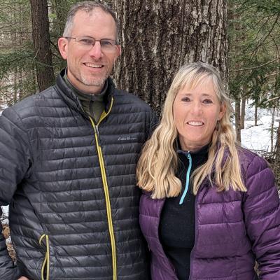 Laura Bonk and Phil Trowbridge stand outside on their property in winter.