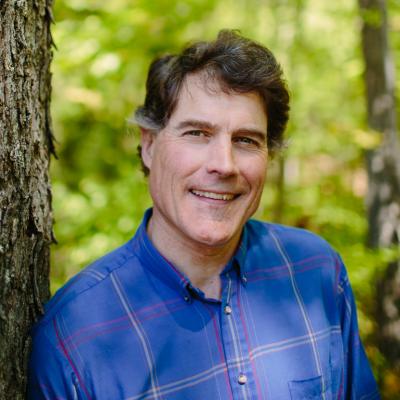 Tom Howe poses in the forest outside of the Conservation Center.