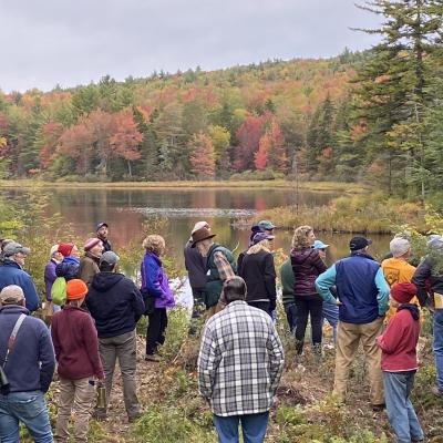 colorful hikers, fall foliage along shore of Morrill Marsh pond, Wilmot