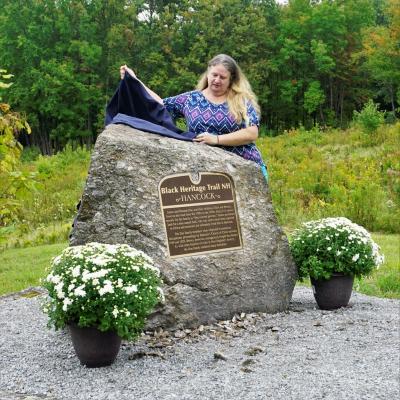 Abigal Atwood Ladd pulls a covering off the rock with the Black Heritage Trail marker during the unveiling ceremony.