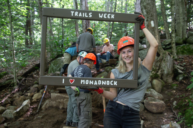 A volunteer poses with a "I love Monadnock" sign frame.