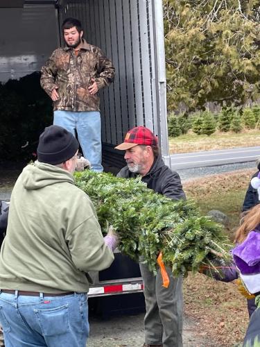 Volunteers pass trees to be loaded into a FedEx truck.