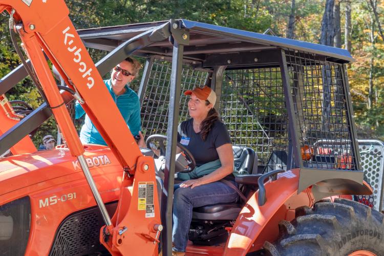 Forest Society Manager Forester Wendy Weisiger helps teach a participant who is driving a tractor.