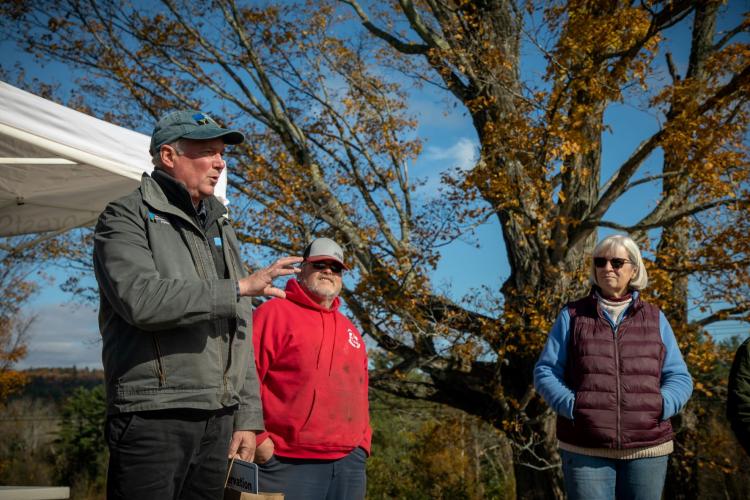 President Jack Savage speaks during the closing ceremony outdoors at Morrill Farm as the owners stand next to him. 