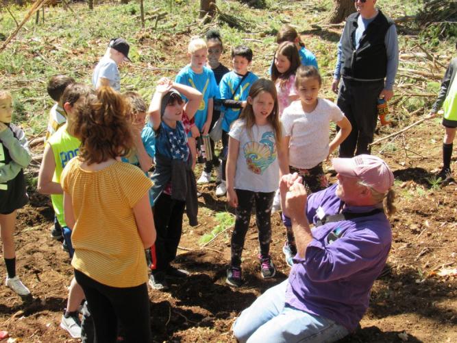 Naturalist kneeling asking students about what trees need